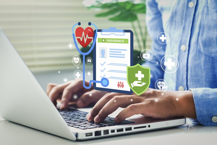 Hands typing on laptop with healthcare icons and digital medical interface.